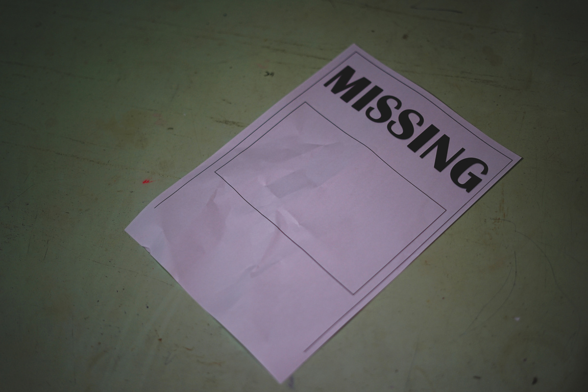 The paper that said Missing lay on the wooden table. Missing person search concept