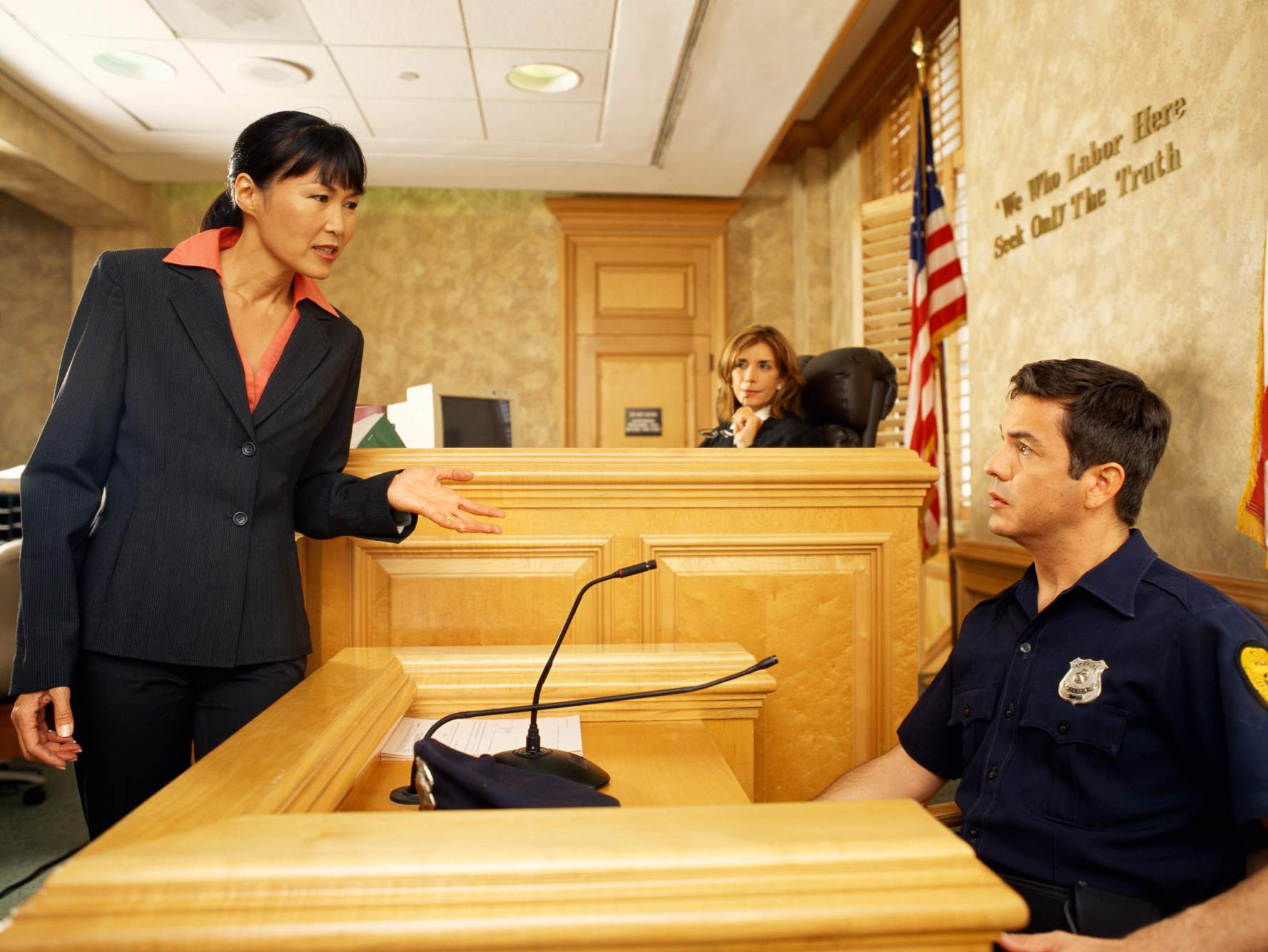 Side profile of a witness and a lawyer on the witness stand, with the judge listening